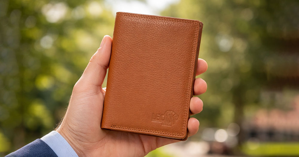 Hand die een bruine leren paspoorthouder vasthoudt